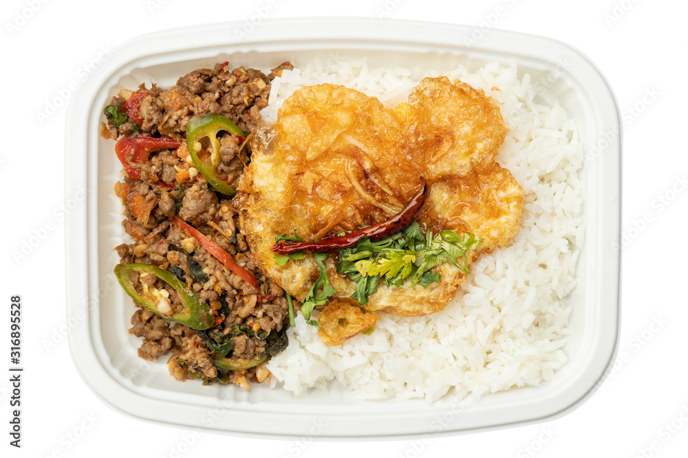 Rice with stir-fried beef and basil leaves and fried egg in food tray isolated on white background
