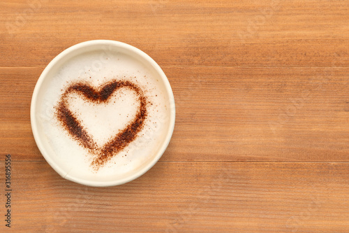Widok z góry filiżankę kawy cappuccino z czekoladą w kształcie serca w proszku na brązowy drewniany stół