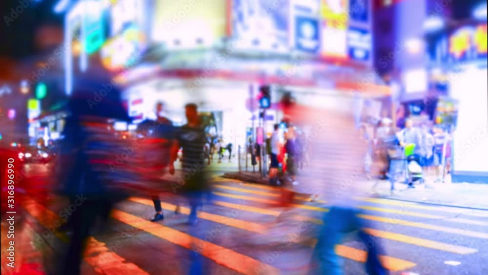 Pedestrians going on crosswalk in Hong Kong in evening. Buildings and skyscrapers illuminated at night. Busy life of asian metropolis with traffic. Tilt shift lens and blur effect. Time lapse