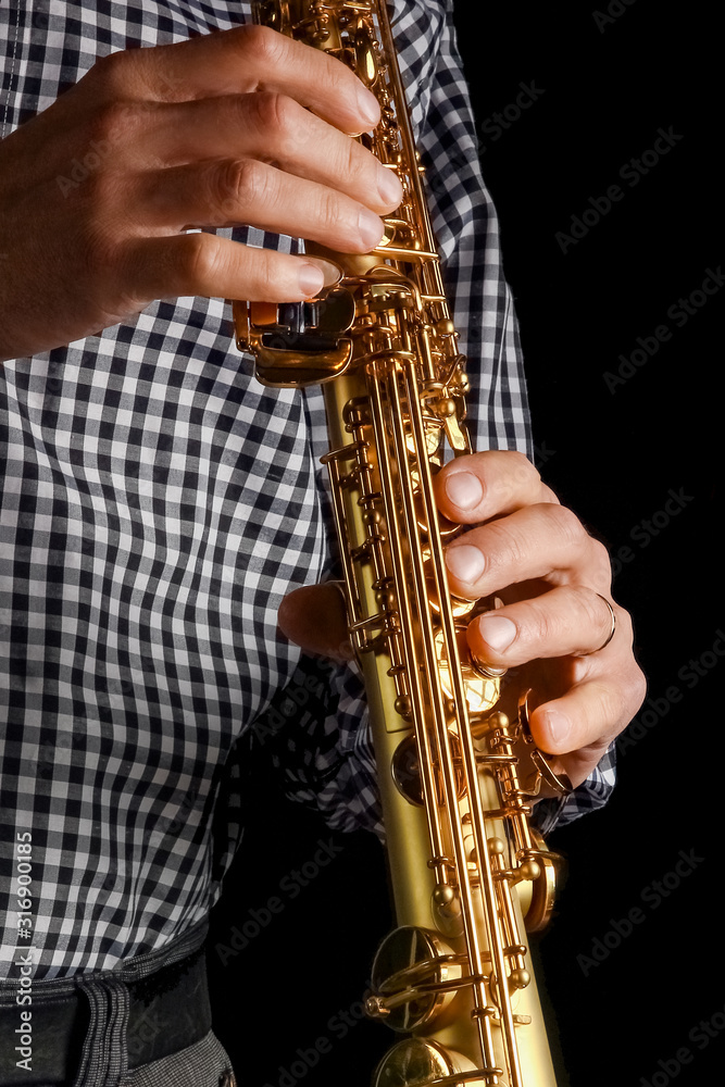 Naklejka premium soprano saxophone in hands on a black background