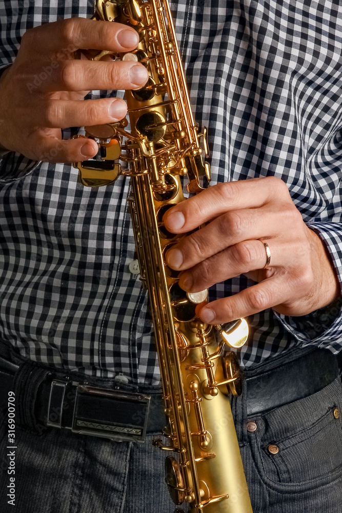 Naklejka premium soprano saxophone in hands on a black background