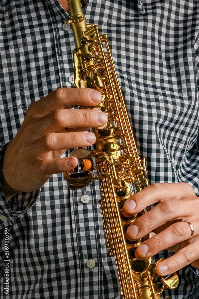 Naklejka premium soprano saxophone in hands on a black background