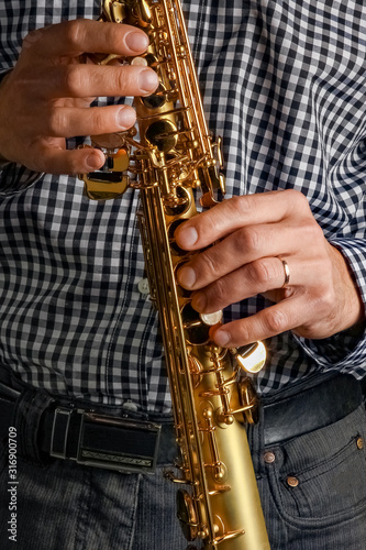 soprano saxophone in hands on a black background