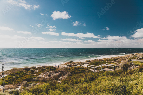 view of Cottesloe beach near Perth with thick vegetations and staircases leading to the sandy shore photo