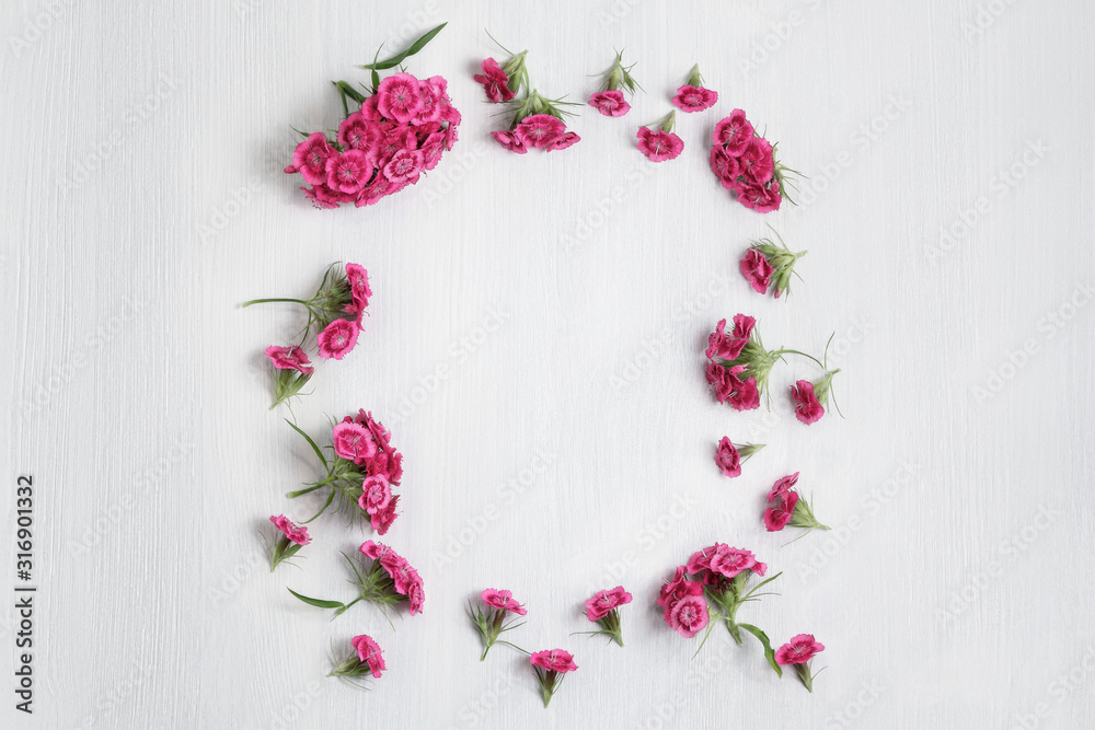 Floral arrangement with copy space. Template for greeting card or design. Frame of pink carnations on a white wooden background