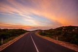Scenic road winding into the distance near the ocean at beautiful sunset