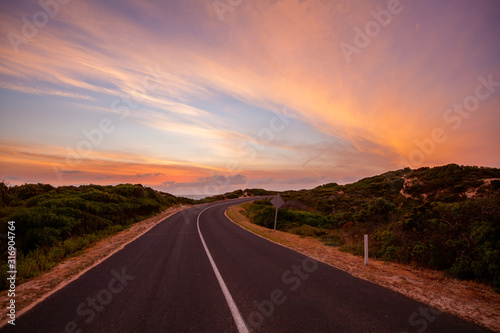 Scenic road winding into the distance near the ocean at beautiful sunset