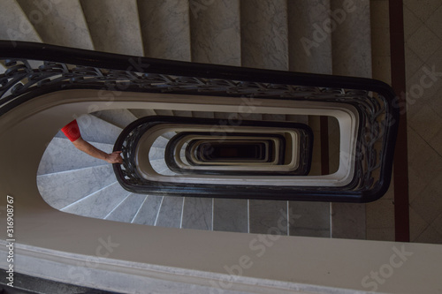 Brazo de una persona bajando las escaleras de un edificio.