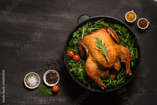 Roasted whole chicken or turkey served in iron pan Placed on black background 