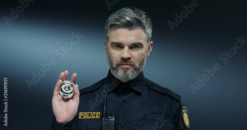 Caucasian good looking policeman showing his badge to the camera like coming to start the arest procedure. Close up. photo