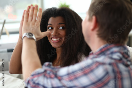 Portrait of man and woman giving high five and smiling. Wife looking at husband with happiness. Close people celebrating success achievement. Friendship and mixed race concept