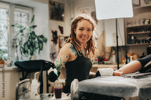 Hipster woman with tattoos dreadlocks makes tattoo