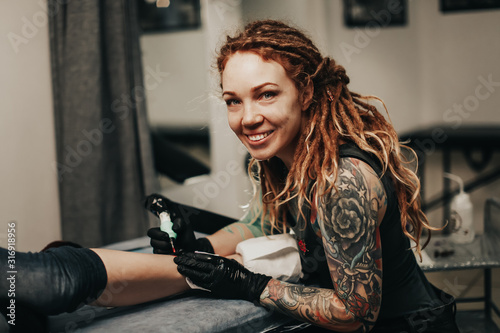 girl with dreadlocks and tattoos stuffs tattoo leg photo