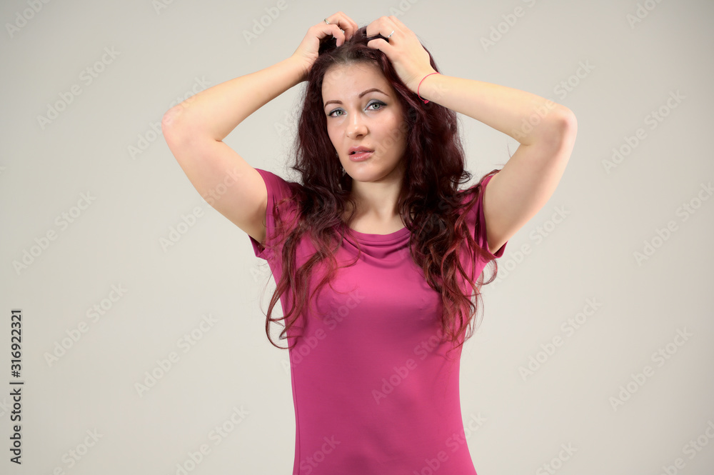 Portrait of a pretty slim brunette woman with emotions in a pink dress and with brown hair on a white background in the studio. The model is smiling and talking nicely. Portrait of a pretty slim brunette woman with emotions in a pink dress and with brown hair on a white background in the studio. The model is smiling and talking nicely.