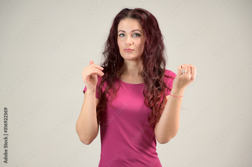 Portrait of a pretty slim brunette woman with emotions in a pink dress and with brown hair on a white background in the studio. The model is smiling and talking nicely. Portrait of a pretty slim brunette woman with emotions in a pink dress and with brown hair on a white background in the studio. The model is smiling and talking nicely.