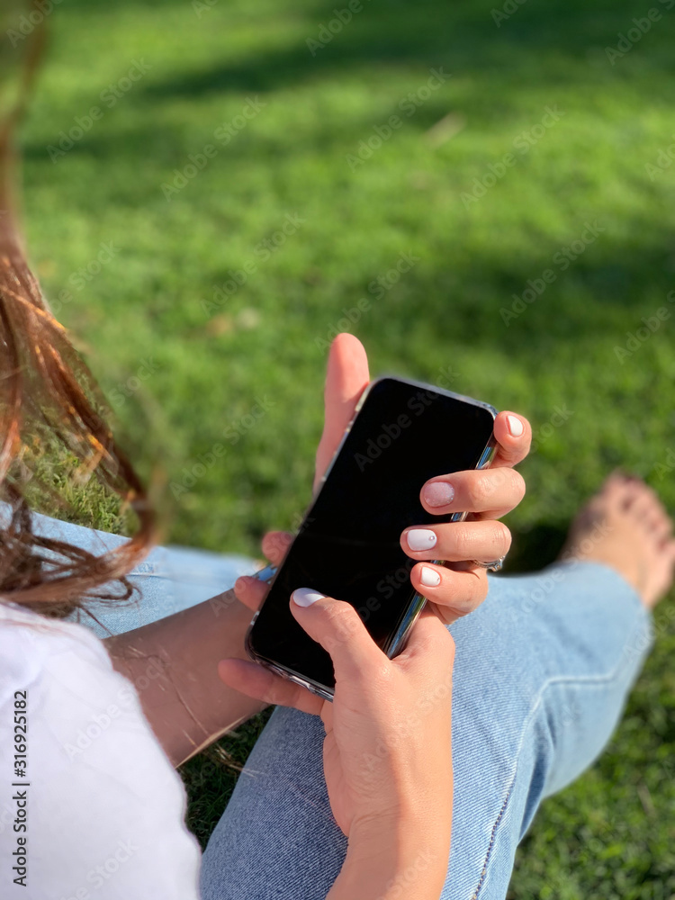 woman with nice manicure using phone in park