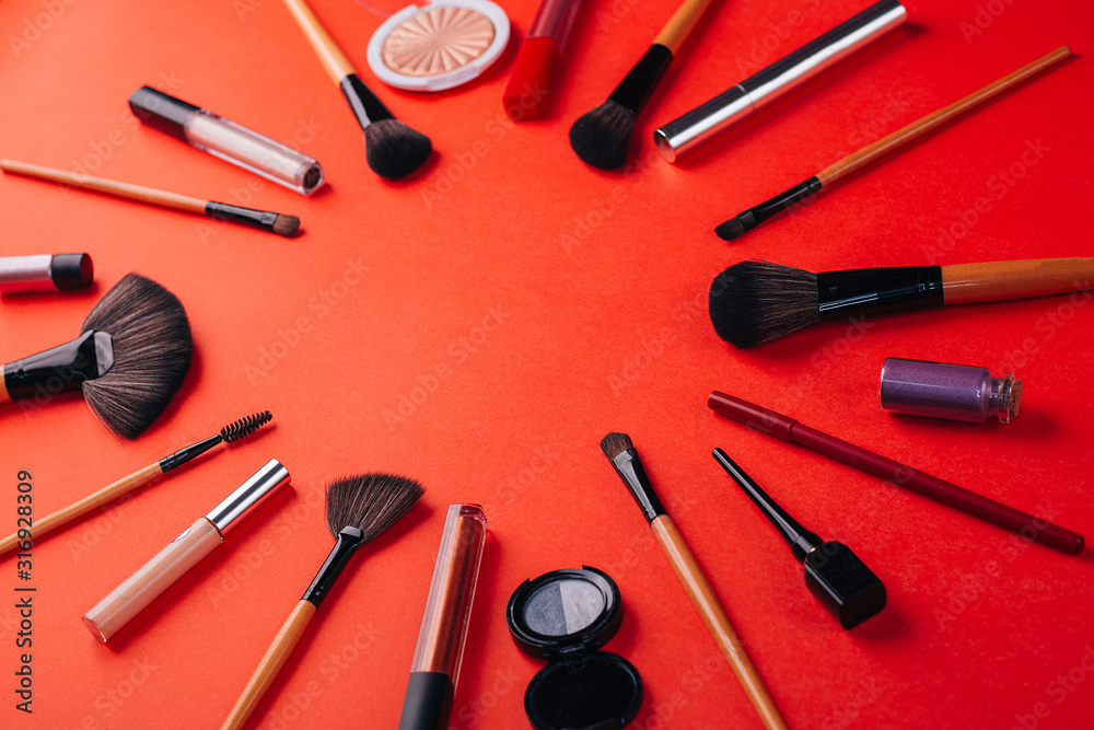 Cosmetics on a bright orange background. Circle of makeup brushes. Cosmetics on a bright orange background. Circle of makeup brushes.