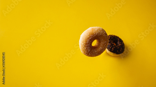 Various decorated doughnuts in motion falling on yelloy background photo