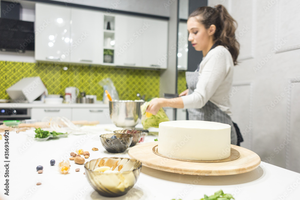 Confectioner smooths white cream on a biscuit cake with a cooking spatula. The concept of homemade pastry, cooking cakes.