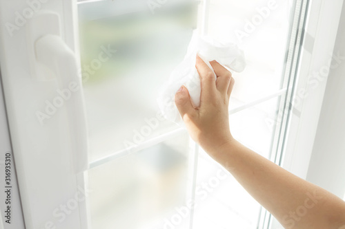 Child hand cleaning window with white rag