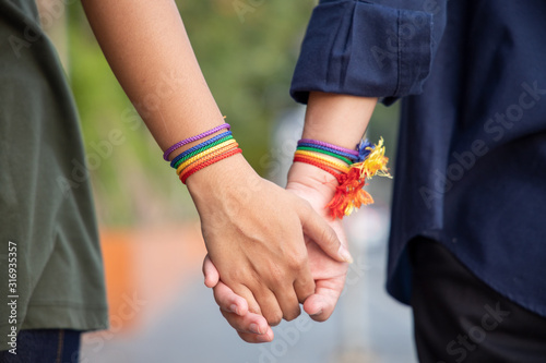 hand of LGBT women holding together with rainbow ribbon symbol; concept of LGBT pride, LGBTQ people, lgbt rights campaign, same sex marriage photo
