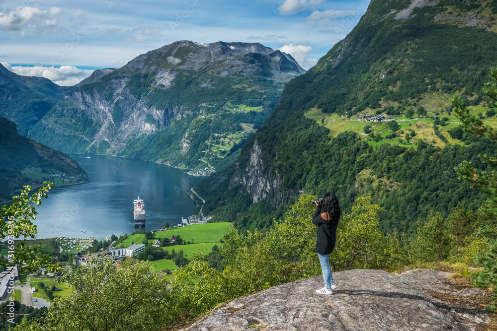 Tourist at the Flydalsjuvet rock looking the Geiranger fjord, Norway Tourist at the Flydalsjuvet rock looking the Geiranger fjord, Norway