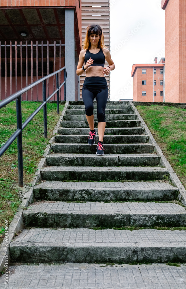 Young female athlete training going down stairs outdoors