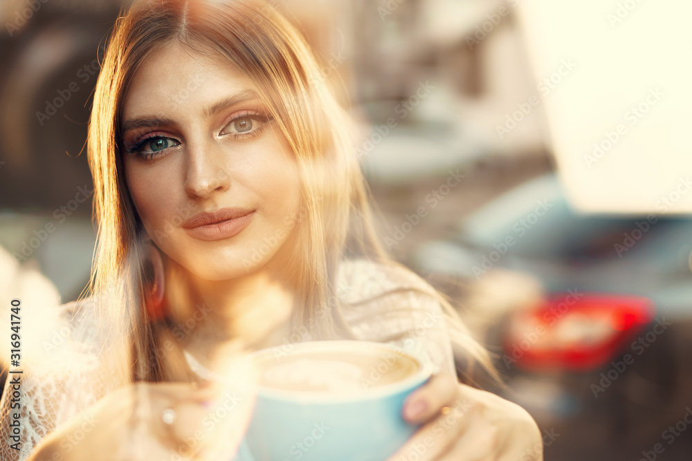 Portrait of a young woman having a cup of coffee and looking through the window Portrait of a young woman having a cup of coffee and looking through the window