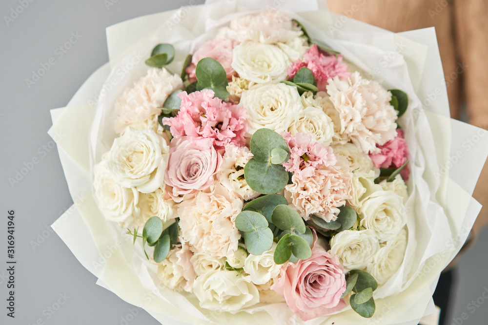 Obraz premium European floral shop. Beautiful bouquet of mixed flowers in womans hands. the work of the florist at a flower shop. Delivery fresh cut flower.