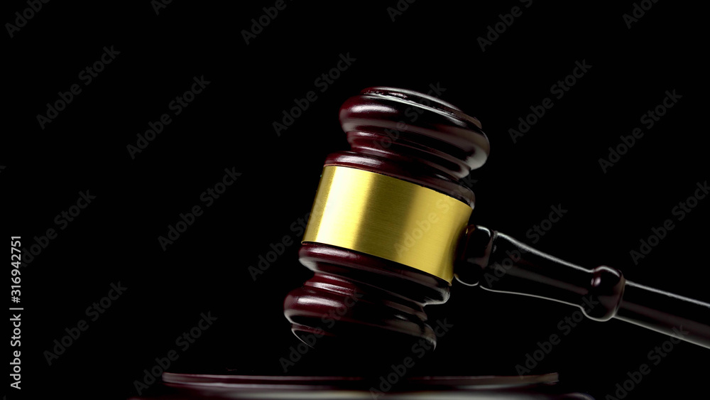 Brass bound wooden gavel resting in the upright position on a plinth, low angle view on a dark background with copyspace conceptual of justice, a judge or auctioneer Brass bound wooden gavel resting in the upright position on a plinth, low angle view on a dark background with copyspace conceptual of justice, a judge or auctioneer