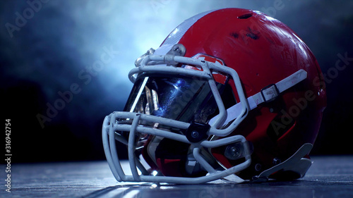 American football player red helmet, close up on a dark background with smoke