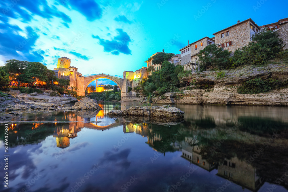 Majestic evening view of Mostar with the Mostar Bridge, houses and minarets, at evening