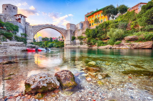 Fantastic Skyline of Mostar with the Mostar Bridge, houses and minarets, at sunset photo
