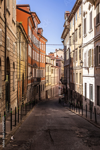 Narrow empty street  via felice venezian  in old town trieste in Italy. Facades of old and colorful mediterranean houses visible.