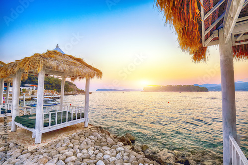 Fototapeta Naklejka Na Ścianę i Meble -  Thatched canopies and awnings on the beach Copacabana at sunset in Dubrovnik