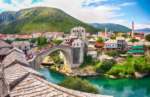 Fantastic Skyline of Mostar with the Mostar Bridge, houses and minarets, during sunny day. photo