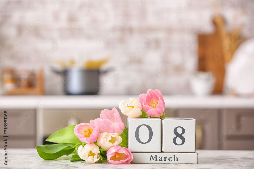 Calendar with date of International Women's Day and flowers on table in kitchen Calendar with date of International Women's Day and flowers on table in kitchen