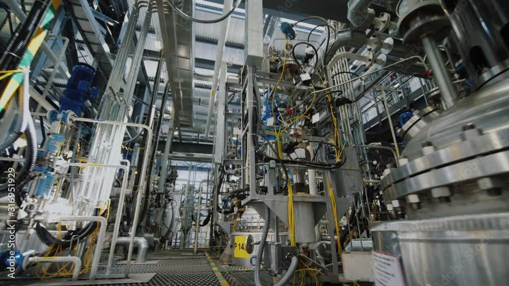 Refinery factory inside. Modern equipment, steel tanks and boilers with cables, pipelines and valves for chemical mixing. Production of anti-turbulent additives used in oil industry