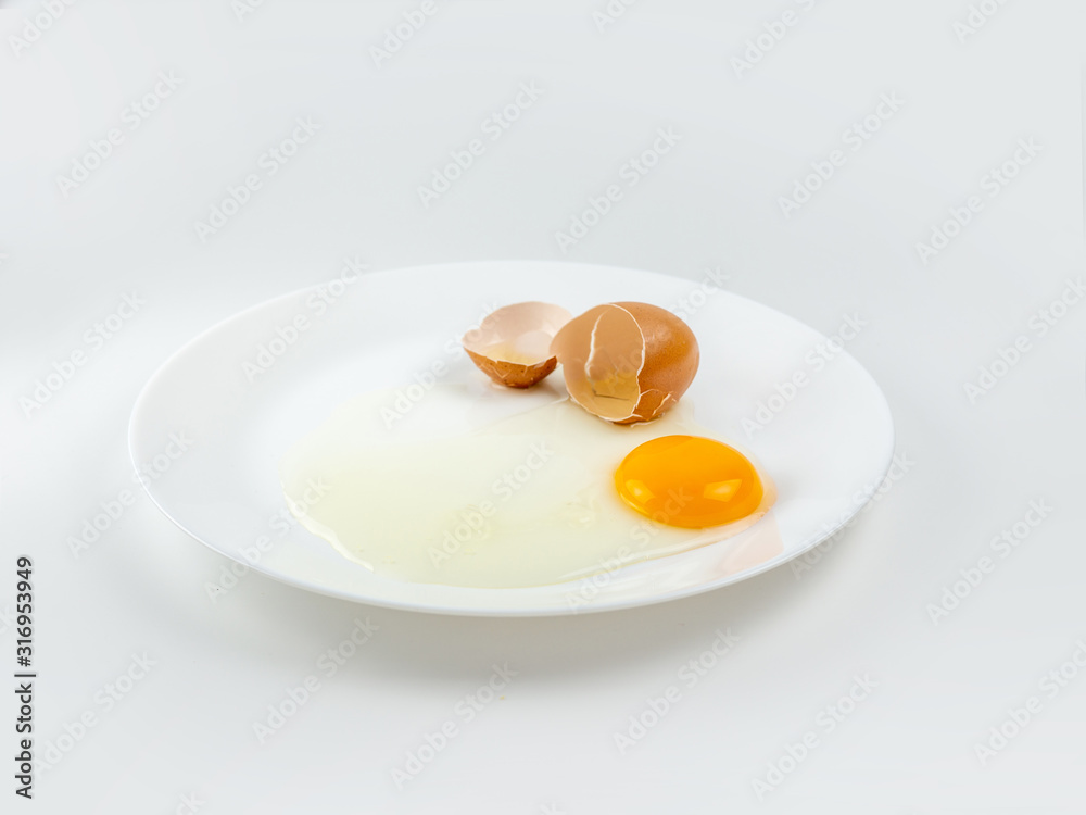 Broken eggs on a plate white background. reddish yellow