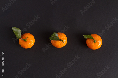 three tangerines on a dark background