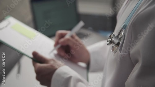 closeup of doctor hand writing dianosis, prescription, notes on clipboard. conclusion of treatment medical report. in clinic, hospital. concept heathcare, medicine, worker