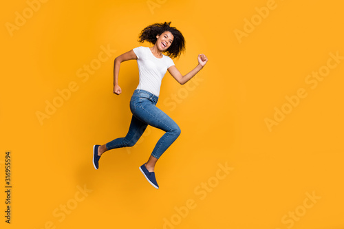 Full length body size photo of cheerful charming cute nice quick millennnial wearing jeans denim white t-shirt footwear running jumping to shopping mall isolated vivid color background