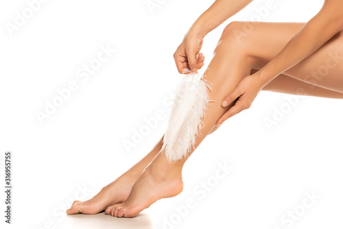 Woman touches her legs with white feather