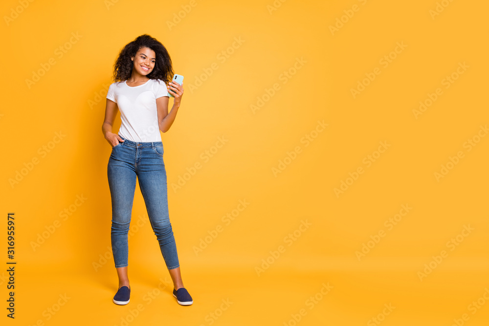 Full length bdoy size photo of cheerful positive nice cute sweet confident girl browsing through her smartphone with hand in pocket of jeans denim isolated vivid color background Full length bdoy size photo of cheerful positive nice cute sweet confident girl browsing through her smartphone with hand in pocket of jeans denim isolated vivid color background