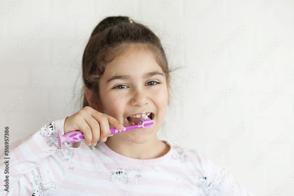 Happy cute little child girl brushing her teeth on light background. Space for text. Healthy teeth. Happy cute little child girl brushing her teeth on light background. Space for text. Healthy teeth.