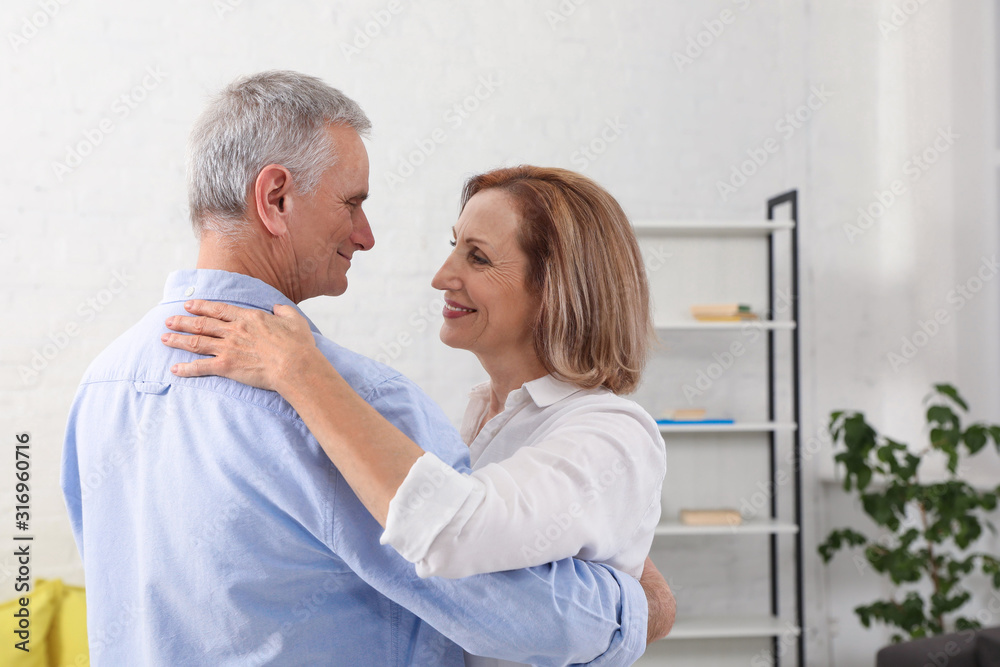Obraz premium Happy senior couple dancing together in living room