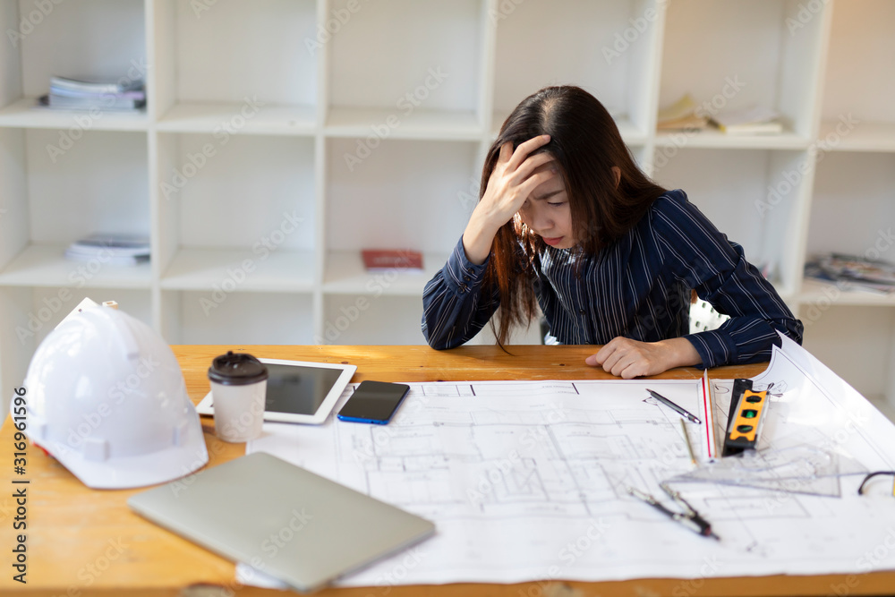 Young woman Architect or engineer stressed at work. Stressed engineer woman working on a laptop. Young woman Architect or engineer stressed at work. Stressed engineer woman working on a laptop.