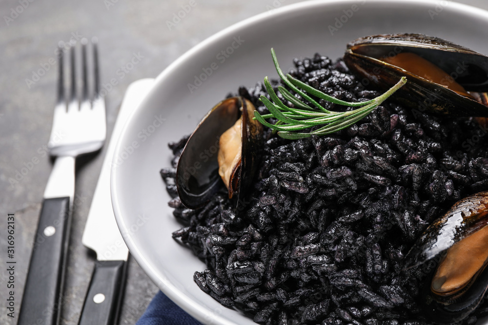 Delicious black risotto with seafood in bowl on table, closeup Delicious black risotto with seafood in bowl on table, closeup
