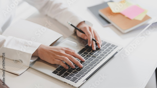 Cropped shot of businesswoman working on laptop and notebook