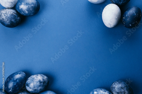 Beautiful group ombre blue Easter eggs with quail eggs and feathers on a blue background. Easter concept. Border eggs. Copy space for text.